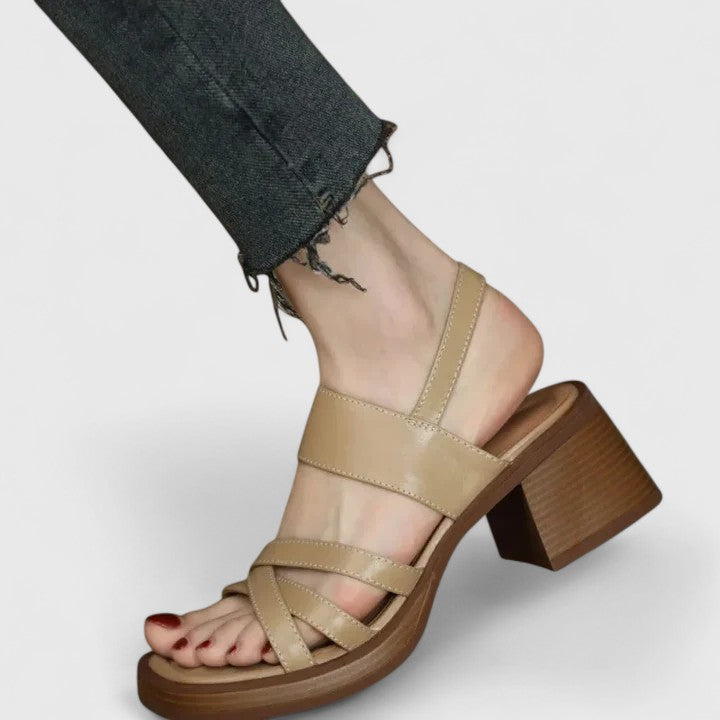 A woman wearing elegant cross-strap sandals with a summer dress, looking graceful and comfortable.