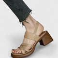 A woman wearing elegant cross-strap sandals with a summer dress, looking graceful and comfortable.