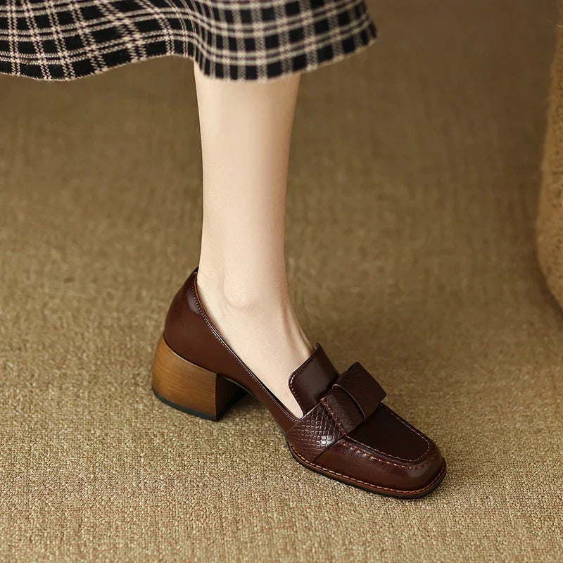A woman wearing classic loafers with a subtle knot detail and tailored pants