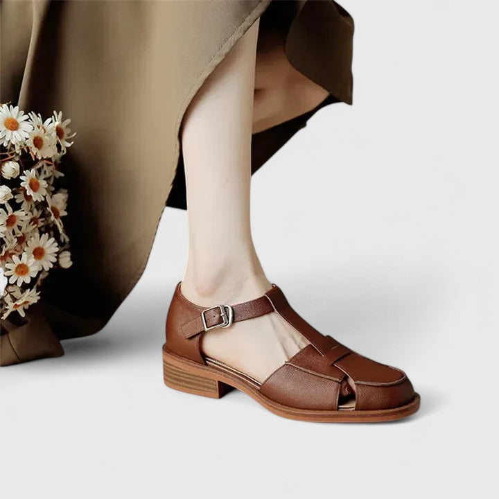 Woman wearing beige strapped Mary Jane sandals on a sunny terrace.