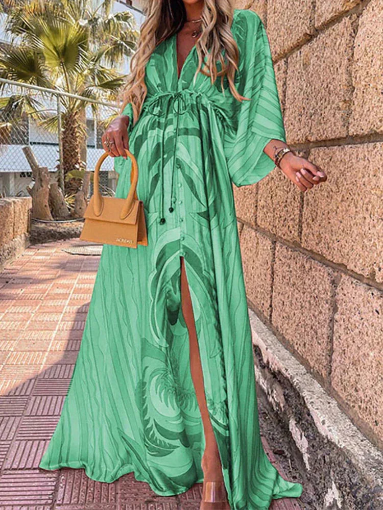Woman wearing a colourful abstract print kaftan maxi dress with flowing sleeves by the water.