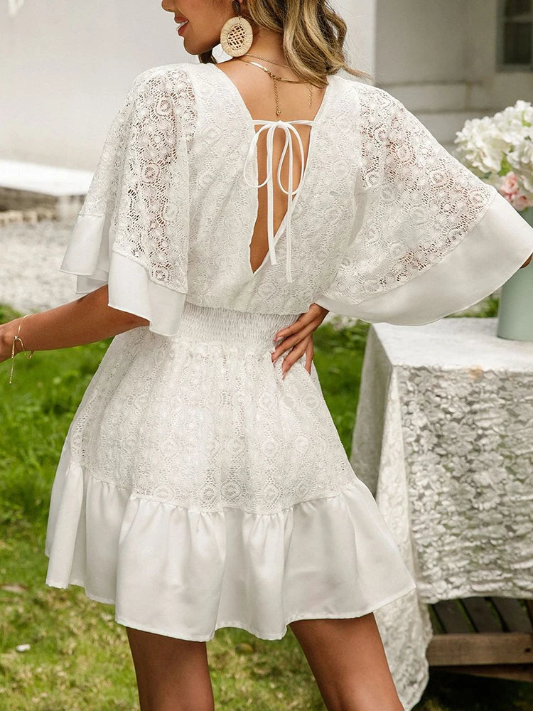 Woman in a delicately detailed boho mini dress with wide floaty sleeves at a garden party.