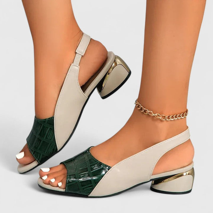 A woman wearing two-tone low-heel dress sandals with an adjustable heel strap at a summer occasion.