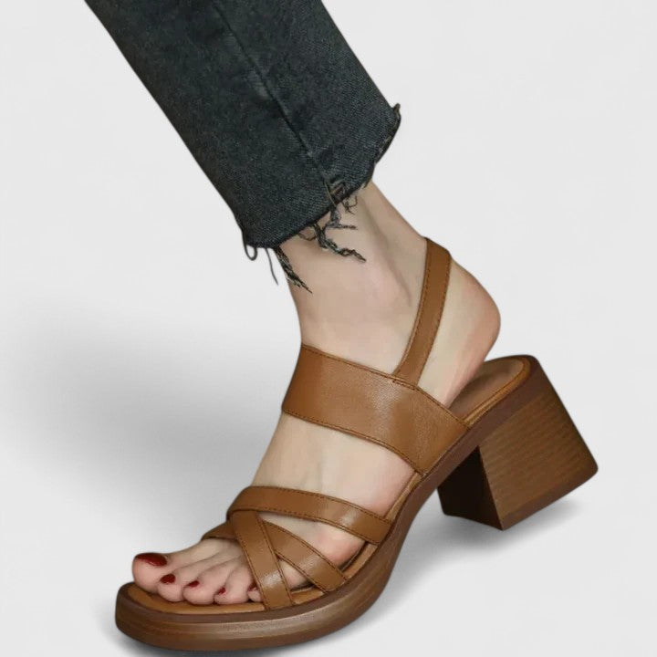 A woman wearing elegant cross-strap sandals with a summer dress, looking graceful and comfortable.