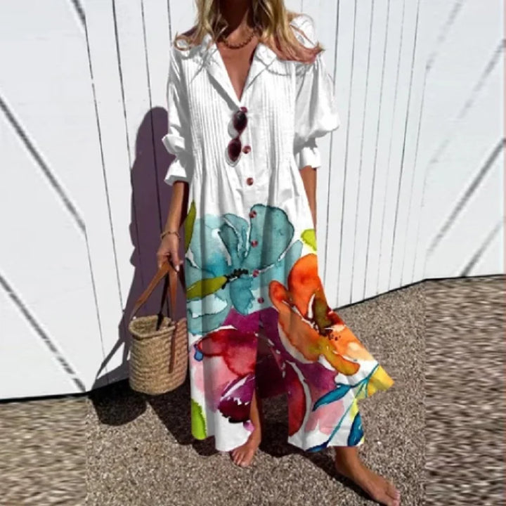 Woman wearing the Gail™ leaf print maxi dress with a button front, walking along the coast in a light breeze.