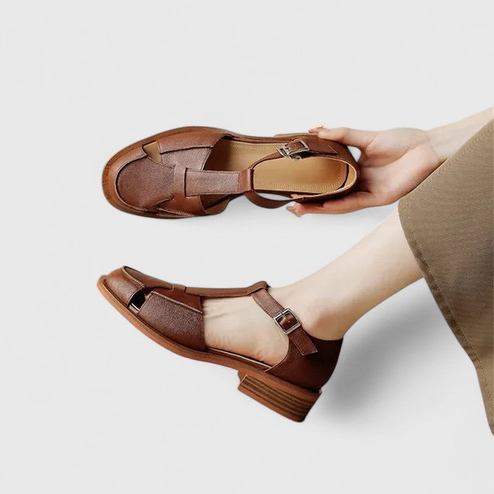 A woman wearing brown Mary Jane sandals with a T-strap and buckle, paired with a summer dress.