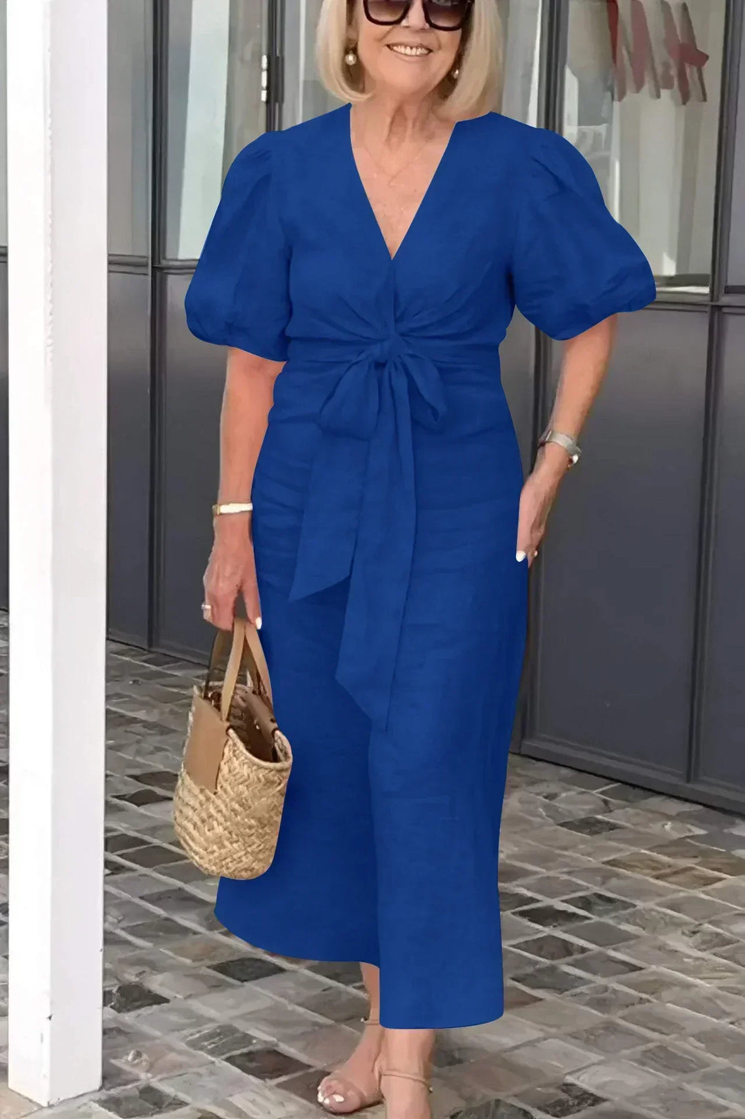 Woman wearing the Christina bow-front midi dress with puff sleeves at a garden party.