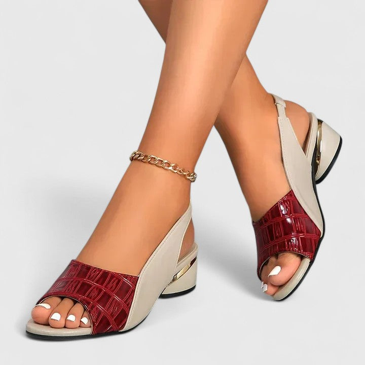 A woman wearing two-tone low-heel dress sandals with an adjustable heel strap at a summer occasion.