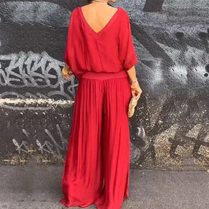 A woman wearing a flowing lounge two-piece set with a V-neck top and wide-leg pants.