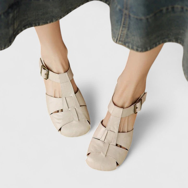 Black closed-toe sandals with a slim T-strap, buckled slingback and a low block heel.