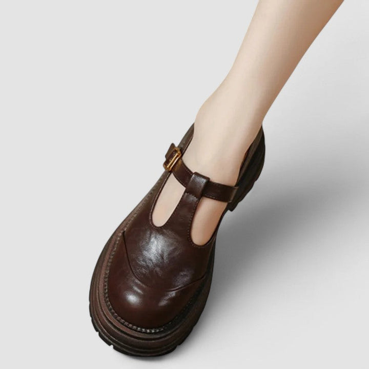 Woman wearing brown Mary Stacey comfort shoes with a T-strap, standing on a city footpath.