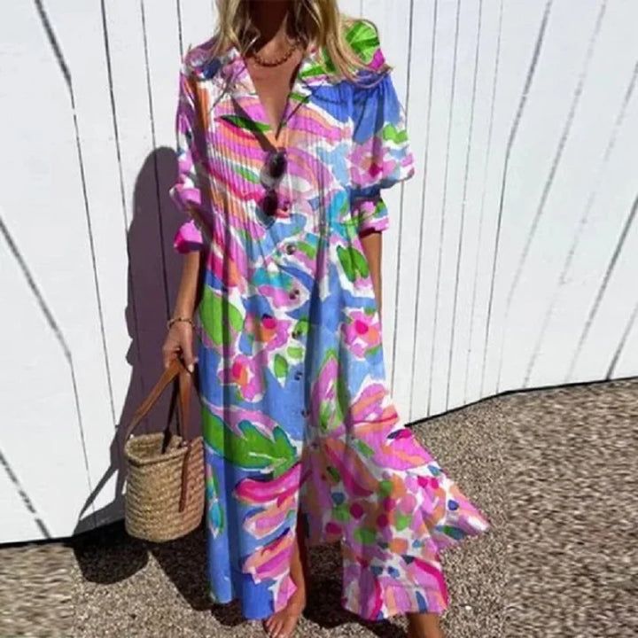 Woman wearing the Gail™ leaf print maxi dress with a button front, walking along the coast in a light breeze.