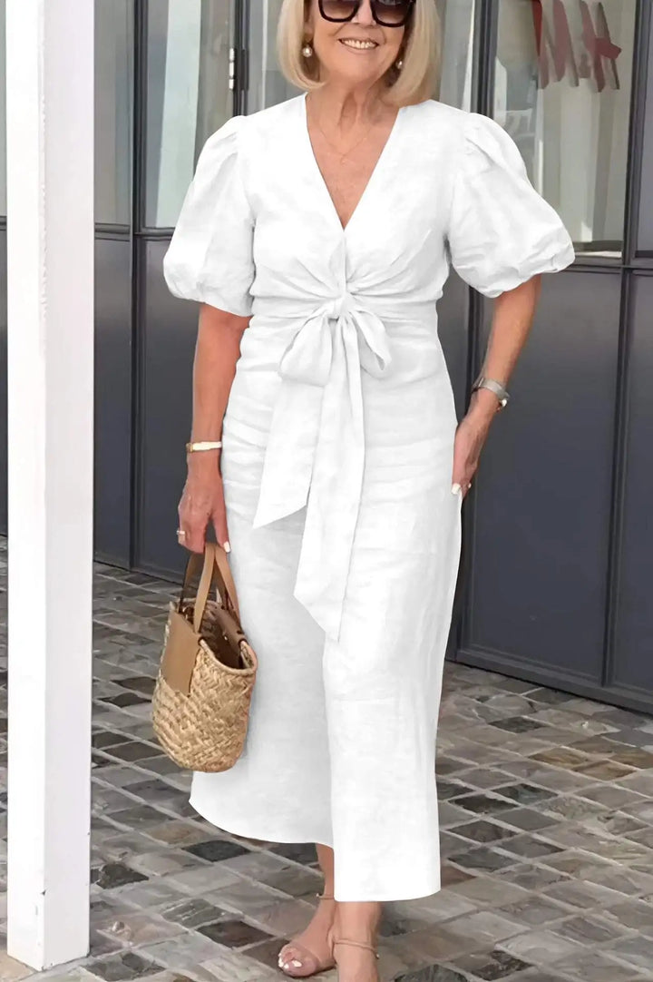 Woman wearing the Christina bow-front midi dress with puff sleeves at a garden party.