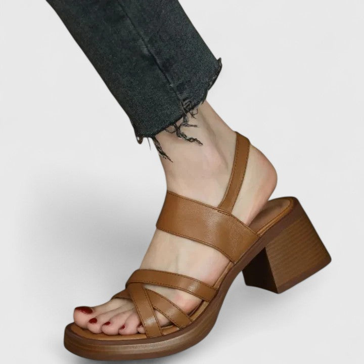 A woman wearing elegant cross-strap sandals with a summer dress, looking graceful and comfortable.