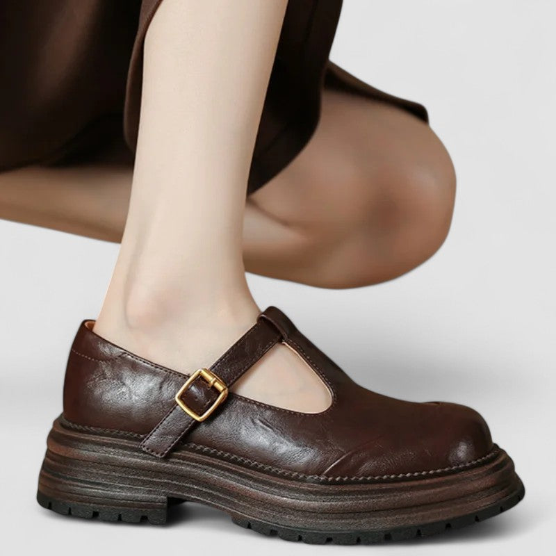 Woman wearing brown Mary Stacey comfort shoes with a T-strap, standing on a city footpath.