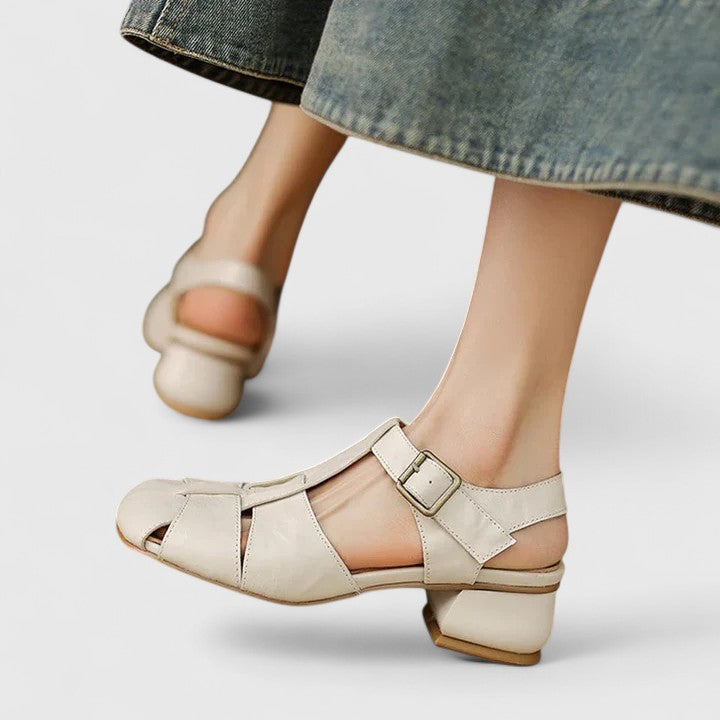 Black closed-toe sandals with a slim T-strap, buckled slingback and a low block heel.