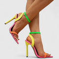 A woman wearing bright neon multicolour stiletto pumps with a slim heel and ankle strap.