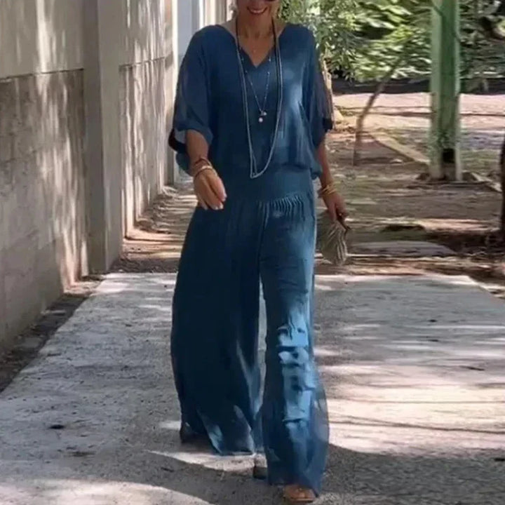 A woman wearing a flowing lounge two-piece set with a V-neck top and wide-leg pants.