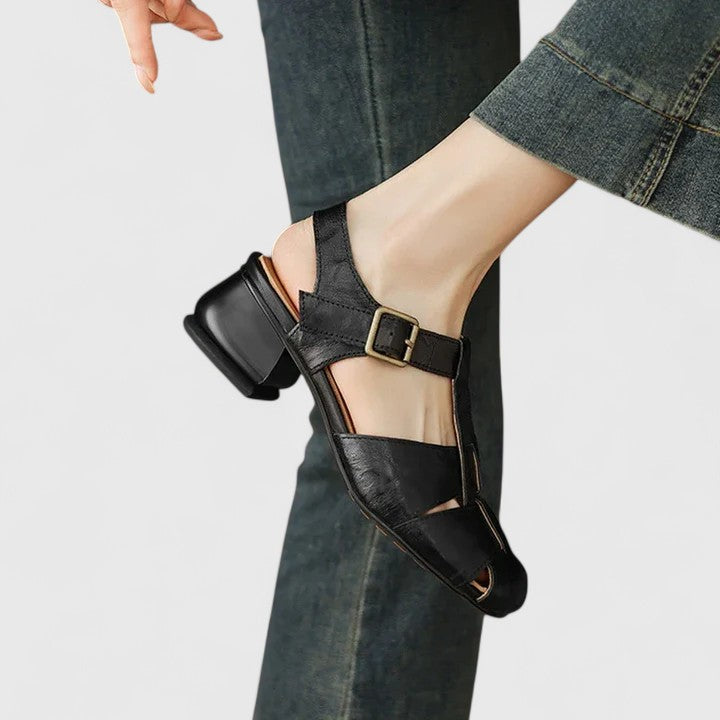 Black closed-toe sandals with a slim T-strap, buckled slingback and a low block heel.