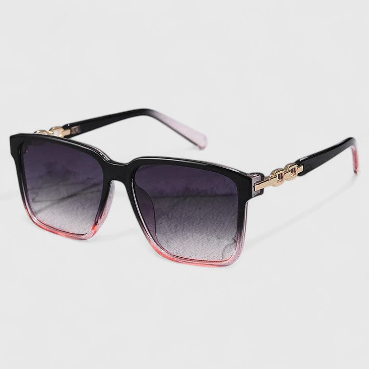 A woman by the pool wearing bold square sunglasses with chain-detail temples, confident in the sun.