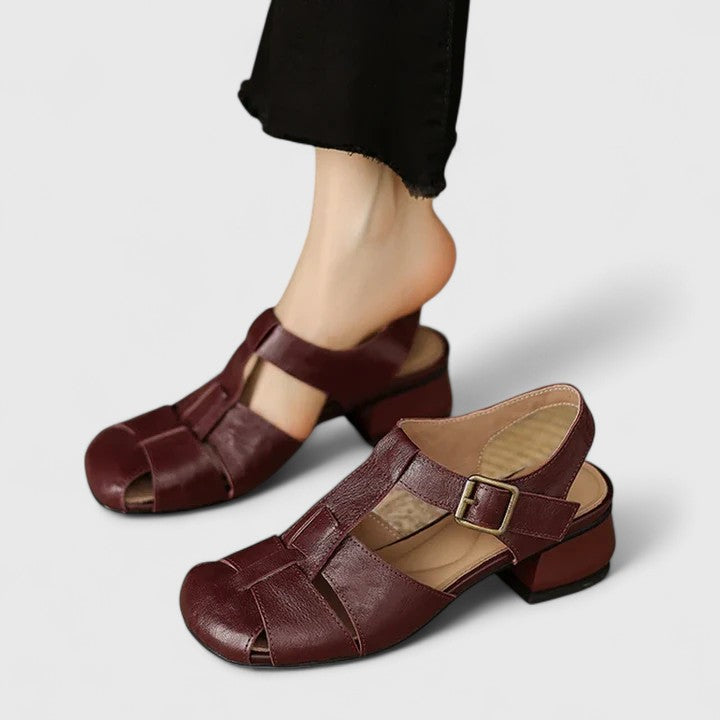 Black closed-toe sandals with a slim T-strap, buckled slingback and a low block heel.