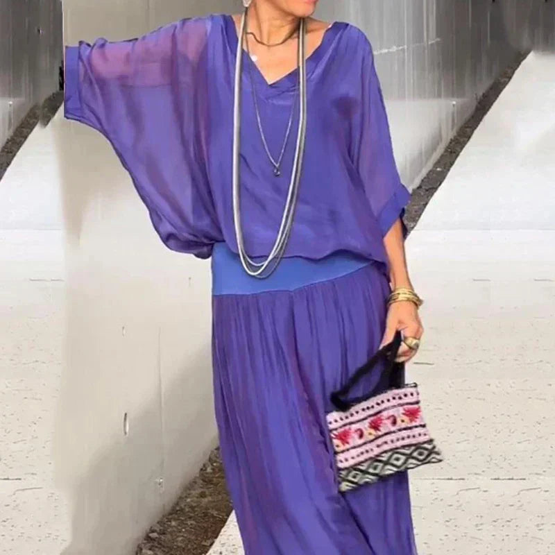 A woman wearing a flowing lounge two-piece set with a V-neck top and wide-leg pants.
