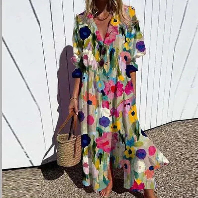 Woman wearing the Gail™ leaf print maxi dress with a button front, walking along the coast in a light breeze.