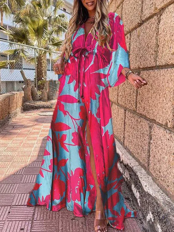 Woman wearing a colourful abstract print kaftan maxi dress with flowing sleeves by the water.