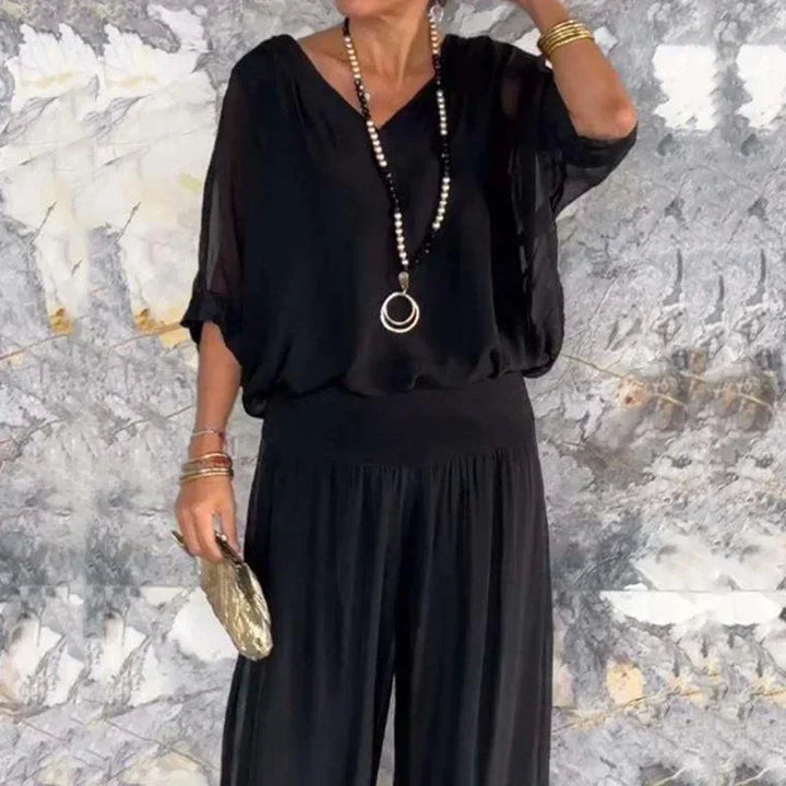 A woman wearing a flowing lounge two-piece set with a V-neck top and wide-leg pants.