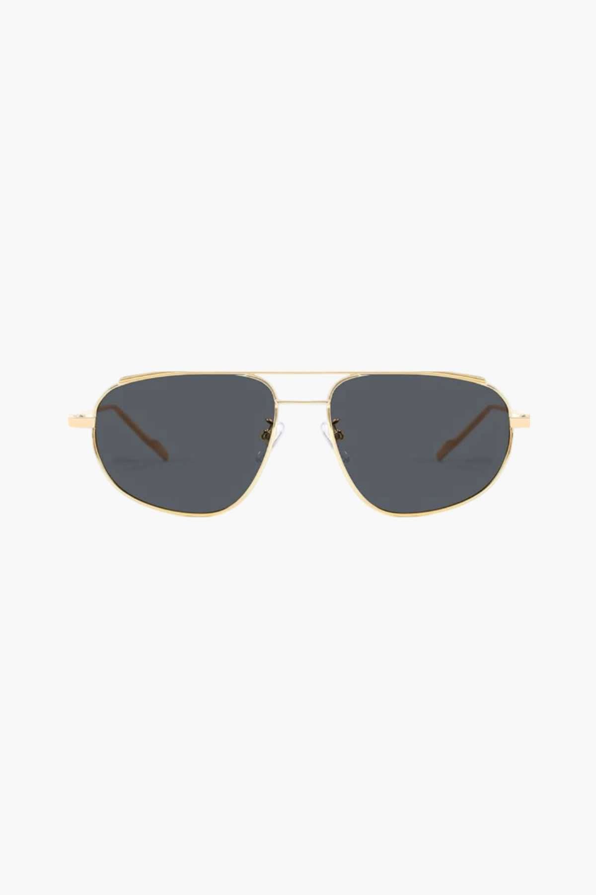 A woman wearing lightweight gold polarised sunglasses on a bright coastal day.