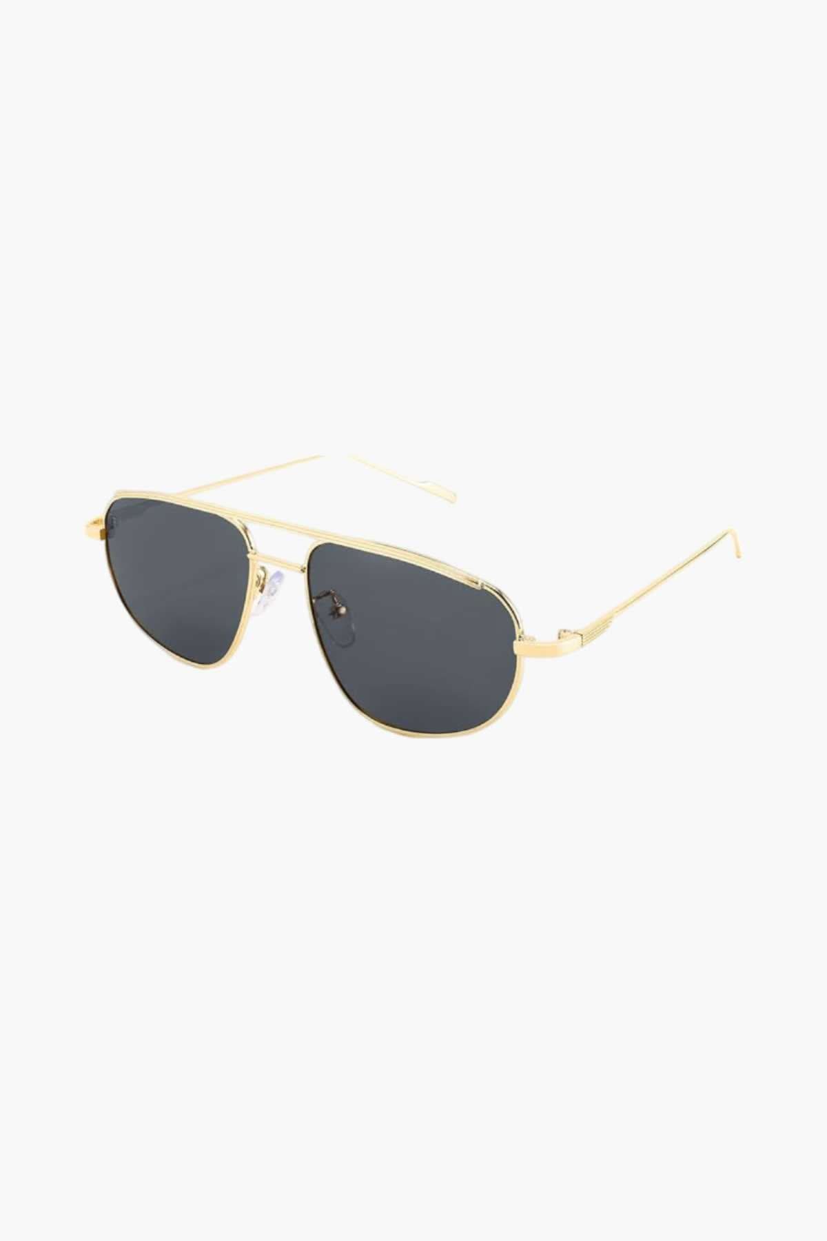 A woman wearing lightweight gold polarised sunglasses on a bright coastal day.