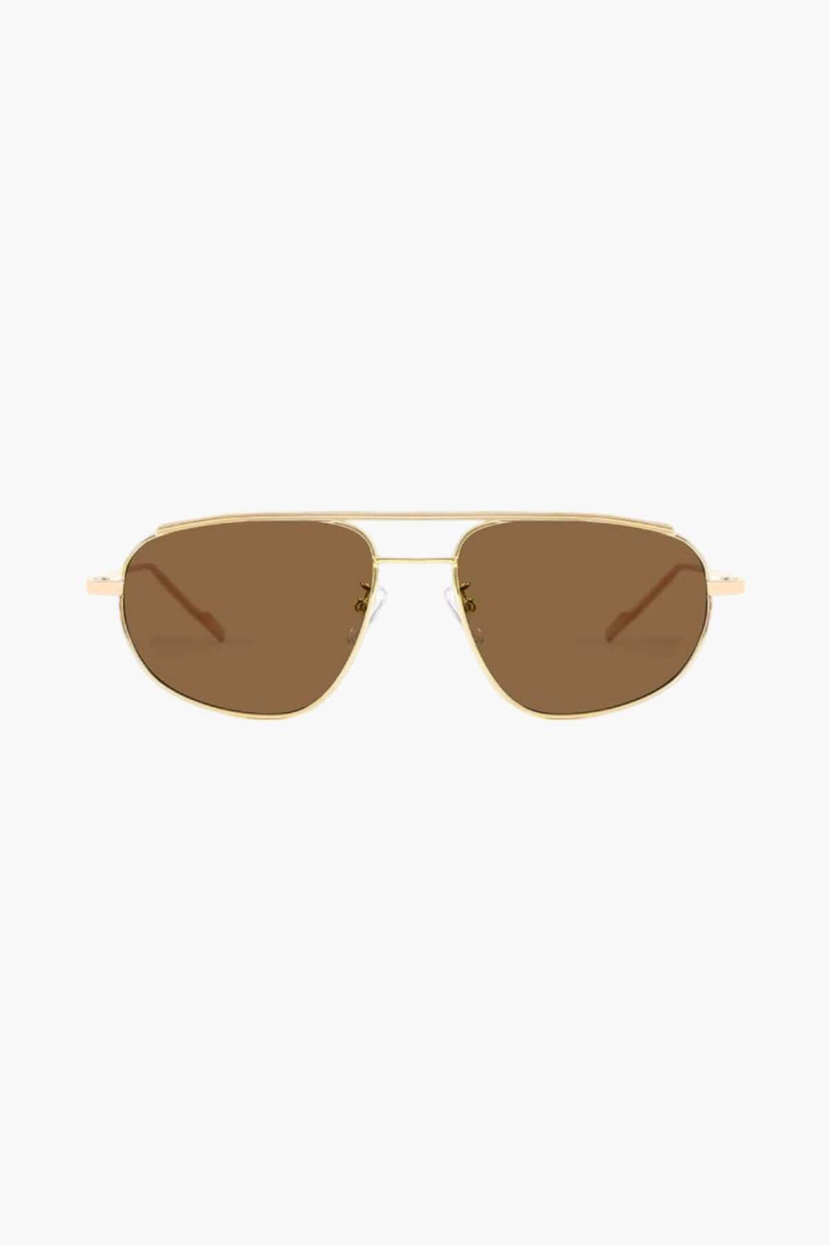 A woman wearing lightweight gold polarised sunglasses on a bright coastal day.