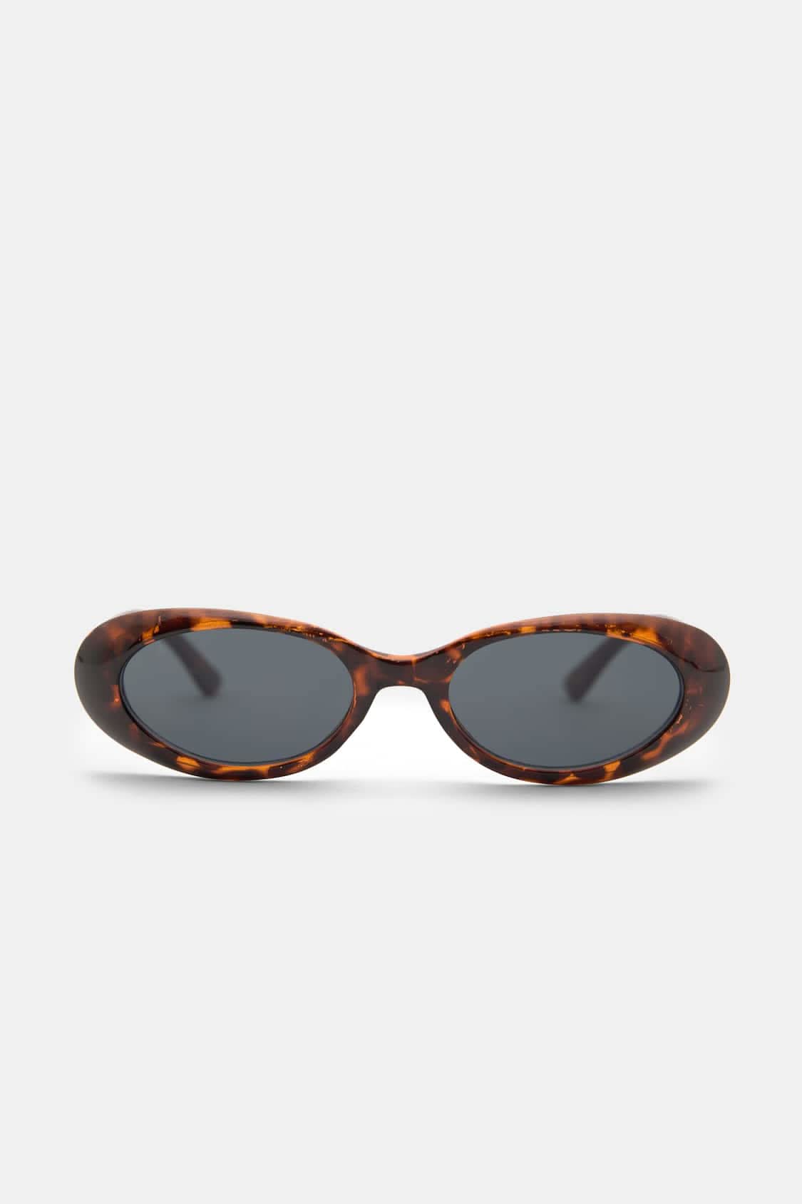 A woman wearing oval retro sunglasses while out shopping on a sunny day.