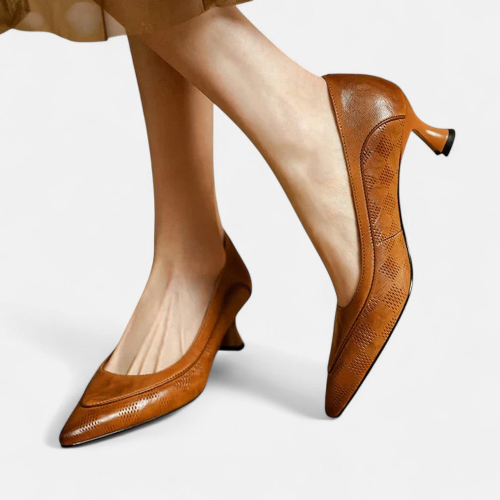 A woman wearing black pointed kitten-heel pumps with a subtle embossed finish.