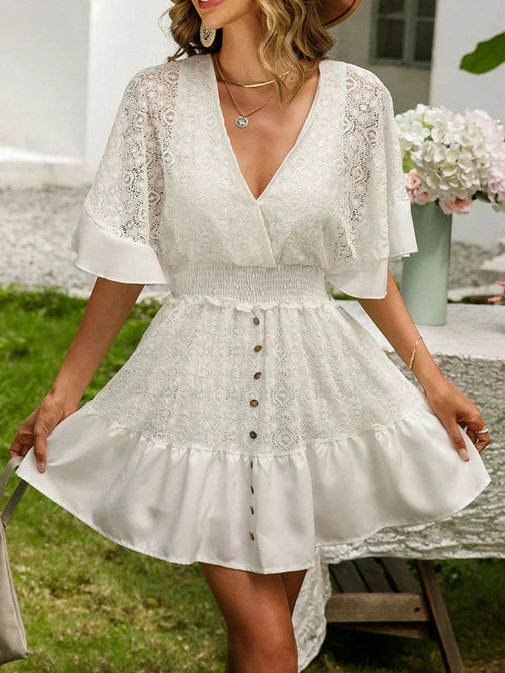 Woman in a delicately detailed boho mini dress with wide floaty sleeves at a garden party.