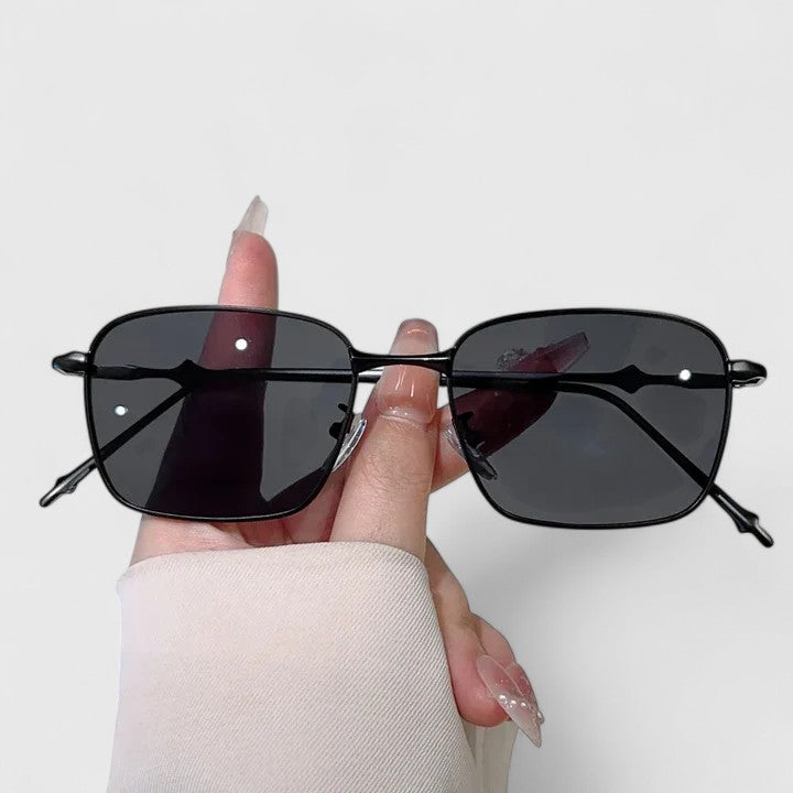 A woman on a sunny street wearing classic square gradient sunglasses, confident and stylish.