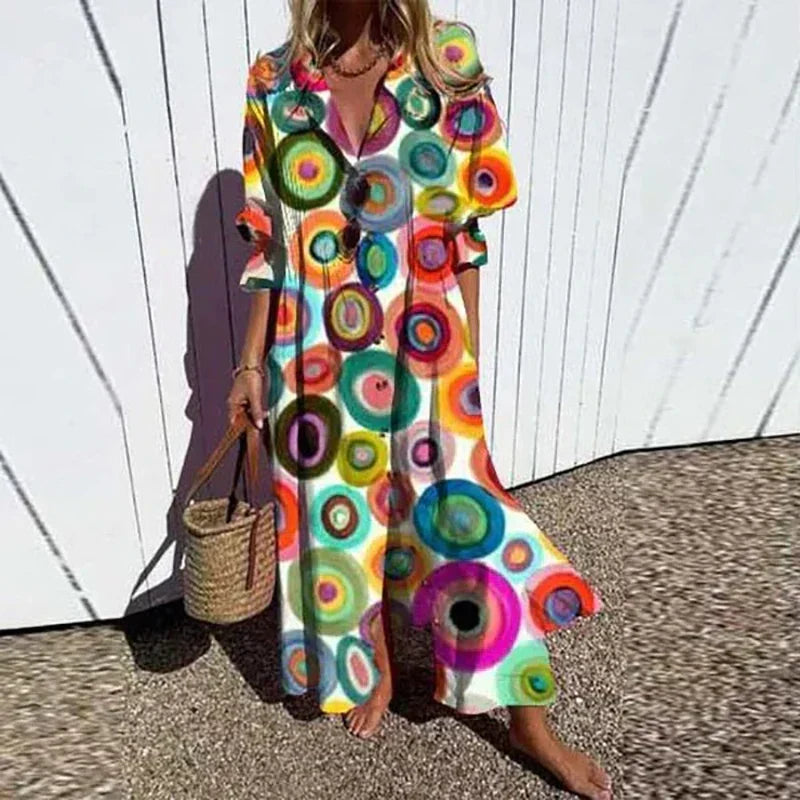 Woman wearing the Gail™ leaf print maxi dress with a button front, walking along the coast in a light breeze.