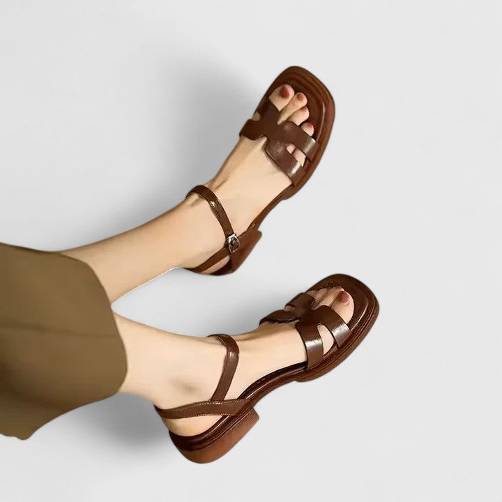 A woman wearing minimalist black strappy sandals with a summer dress, looking chic and at ease.