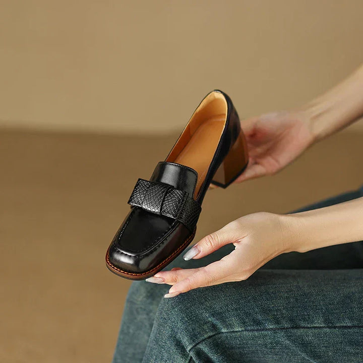 A woman wearing classic loafers with a subtle knot detail and tailored pants