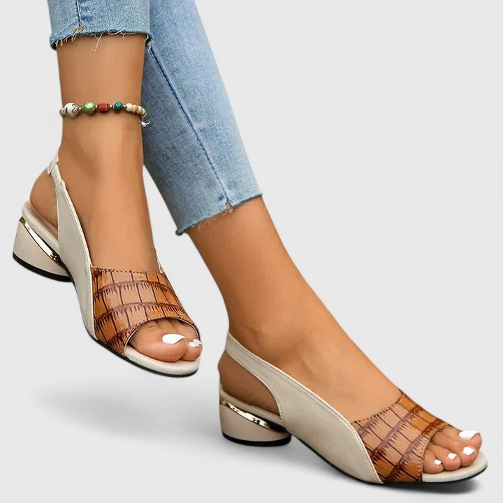 A woman wearing two-tone low-heel dress sandals with an adjustable heel strap at a summer occasion.