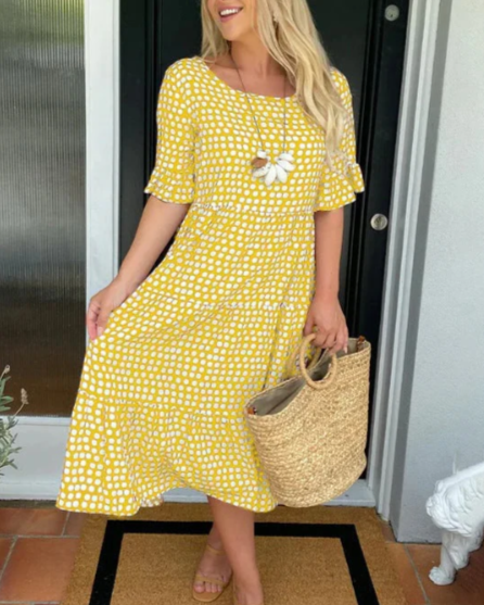 A woman wearing the Tammy short sleeve midi dress with a flowing skirt on a warm day.