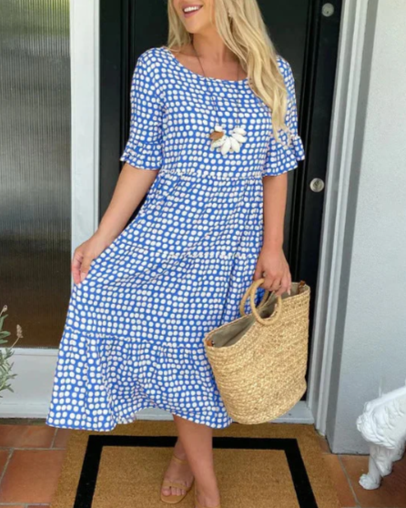 A woman wearing the Tammy short sleeve midi dress with a flowing skirt on a warm day.