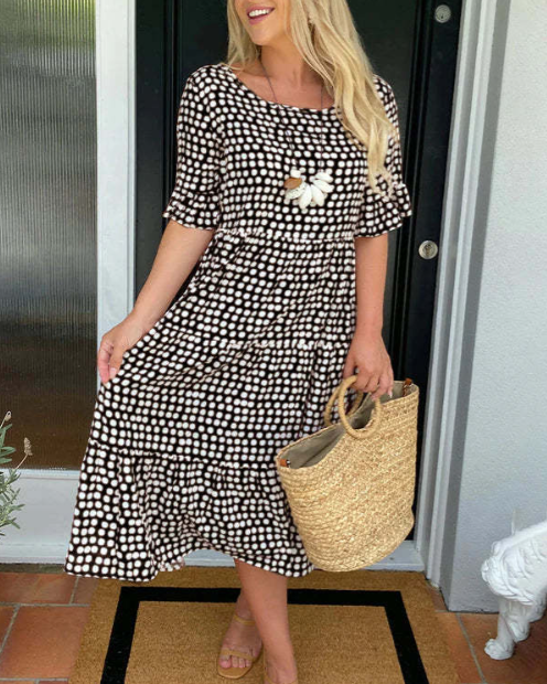 A woman wearing the Tammy short sleeve midi dress with a flowing skirt on a warm day.