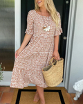A woman wearing the Tammy short sleeve midi dress with a flowing skirt on a warm day.