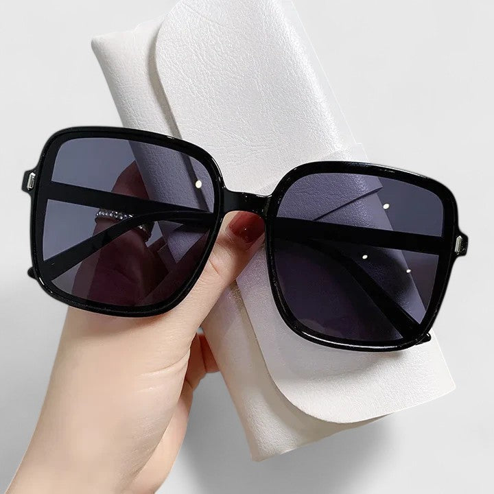 A woman wearing vintage-inspired oversized sunglasses in the sun, elegant and relaxed.