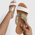 A woman wearing metallic golden slip-on slide sandals with a double strap on a summer evening.