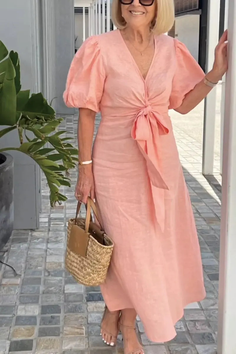Woman wearing the Christina bow-front midi dress with puff sleeves at a garden party.