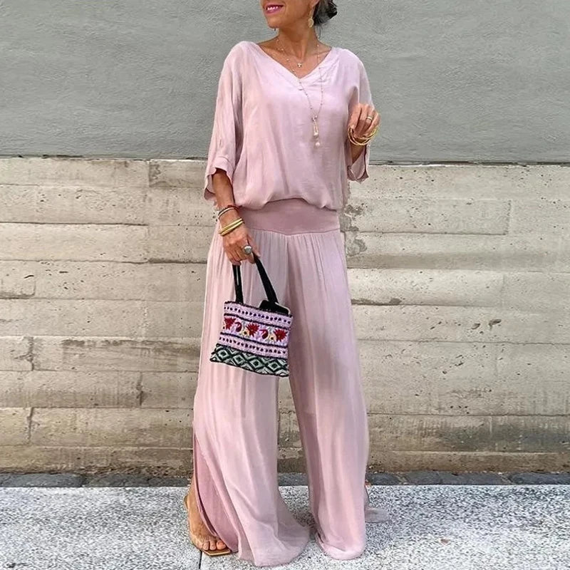 A woman wearing a flowing lounge two-piece set with a V-neck top and wide-leg pants.