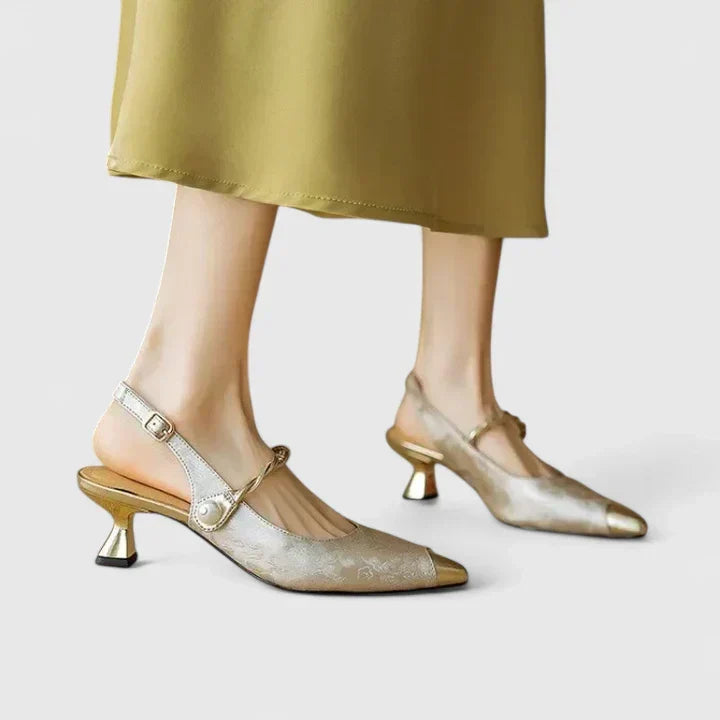 A woman standing elegantly in low cushioned kitten heels with a wide, supportive fit.