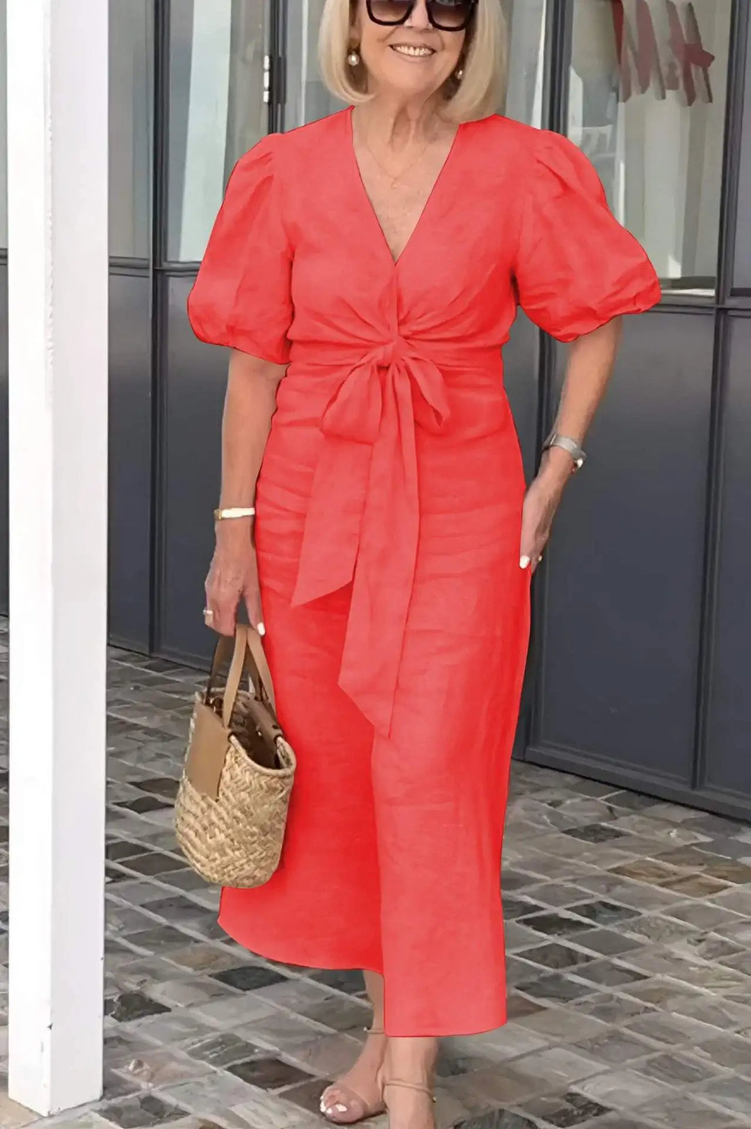 Woman wearing the Christina bow-front midi dress with puff sleeves at a garden party.